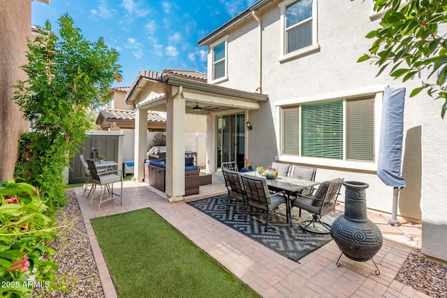 rear view of property with stucco siding, a patio area, ceiling fan, fence, and an outdoor living space