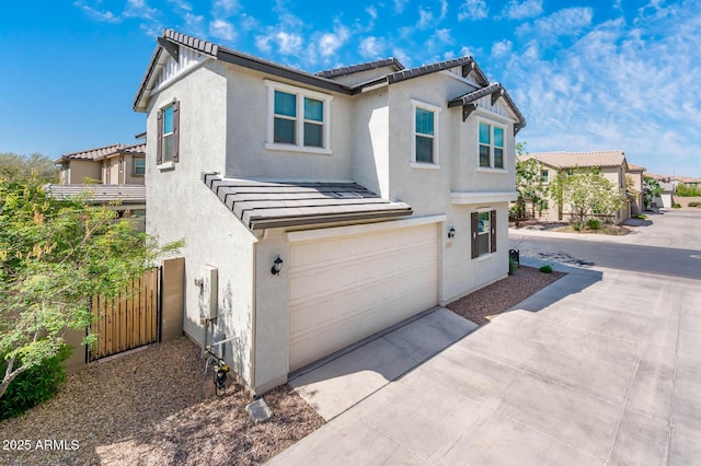 view of front of house featuring an attached garage, stucco siding, a tile roof, and concrete driveway