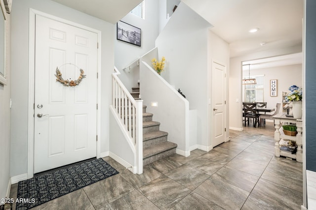 foyer entrance featuring stairway, baseboards, recessed lighting, and a chandelier