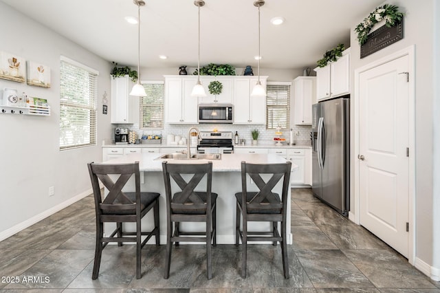 kitchen featuring appliances with stainless steel finishes, a sink, baseboards, plenty of natural light, and recessed lighting