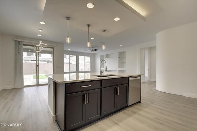 kitchen featuring sink, hanging light fixtures, light wood-type flooring, dishwasher, and an island with sink