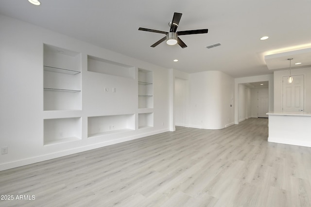 unfurnished living room featuring built in shelves, light hardwood / wood-style flooring, and ceiling fan