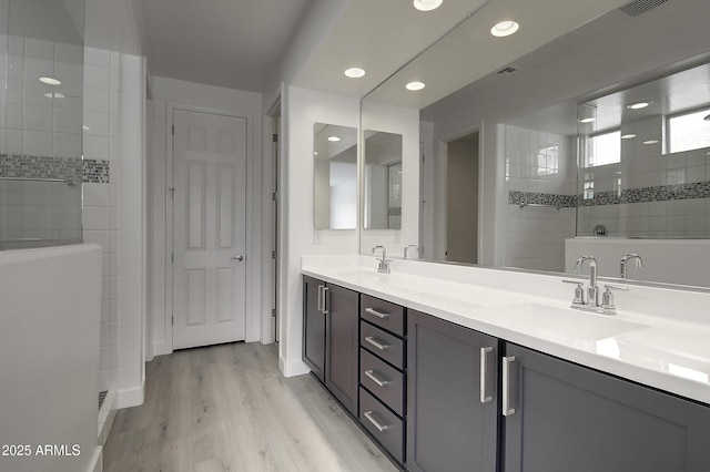 bathroom with hardwood / wood-style flooring, vanity, and a tile shower