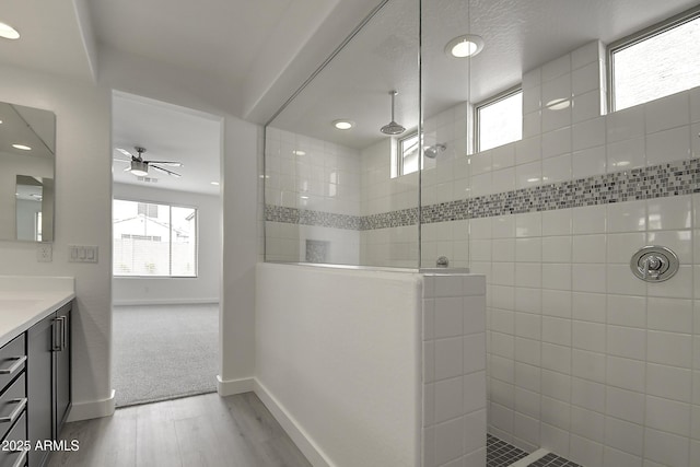 bathroom with vanity, ceiling fan, wood-type flooring, and tiled shower