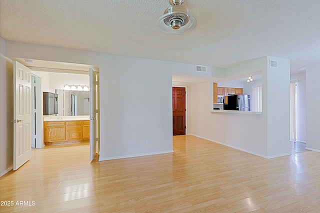 9355 N 91st St Unit 116, Scottsdale, AZ 85258 - unfurnished living room featuring visible vents, a textured ceiling, and light wood-style floors