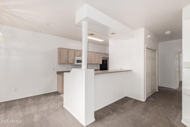 kitchen featuring black fridge, kitchen peninsula, carpet floors, and light brown cabinets