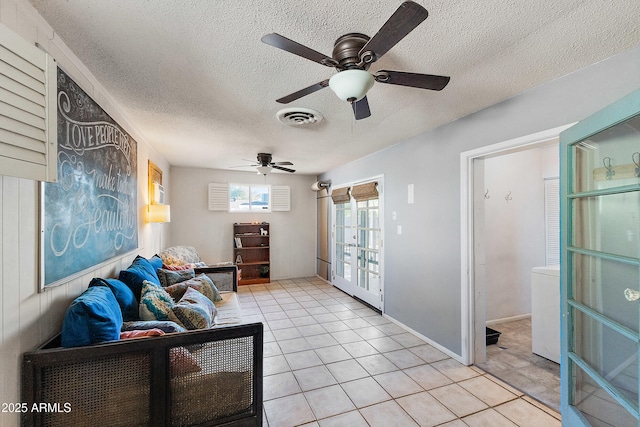 living area featuring light tile patterned floors, a textured ceiling, visible vents, and ceiling fan