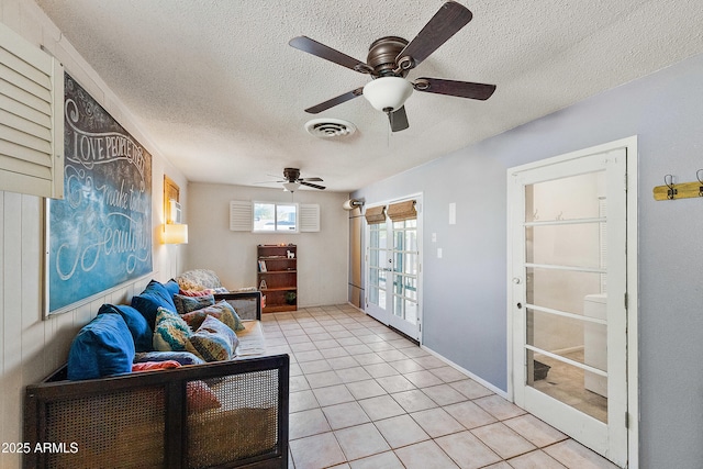 living room with light tile patterned floors, a textured ceiling, visible vents, and ceiling fan