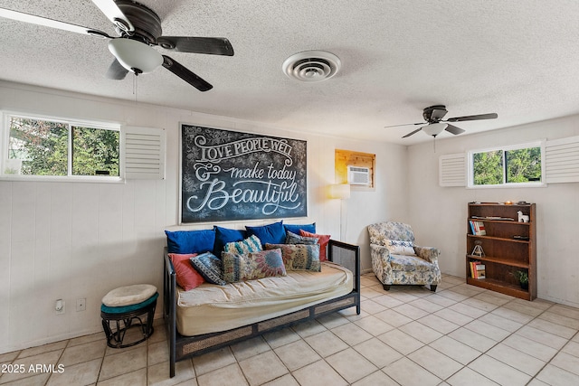 living area featuring a ceiling fan, visible vents, tile patterned floors, and a textured ceiling