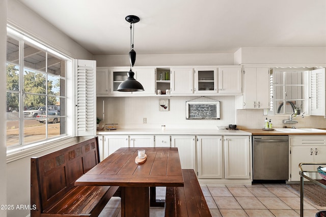 kitchen with stainless steel dishwasher, light countertops, backsplash, a sink, and pendant lighting
