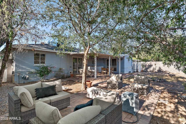 rear view of property with an outdoor living space with a fire pit, fence, french doors, and a patio area