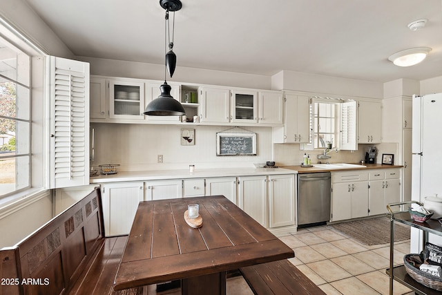 kitchen featuring glass insert cabinets, light countertops, dishwasher, white cabinetry, and pendant lighting