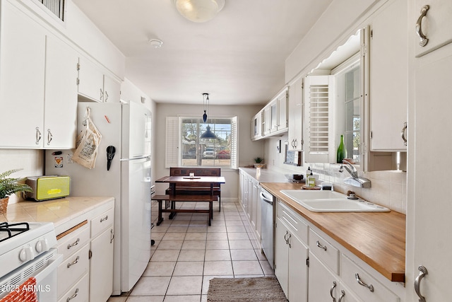 kitchen featuring a sink, decorative backsplash, light tile patterned floors, white cabinetry, and white appliances