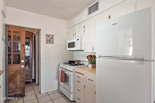 kitchen featuring white appliances, light tile patterned floors, light countertops, baseboards, and visible vents