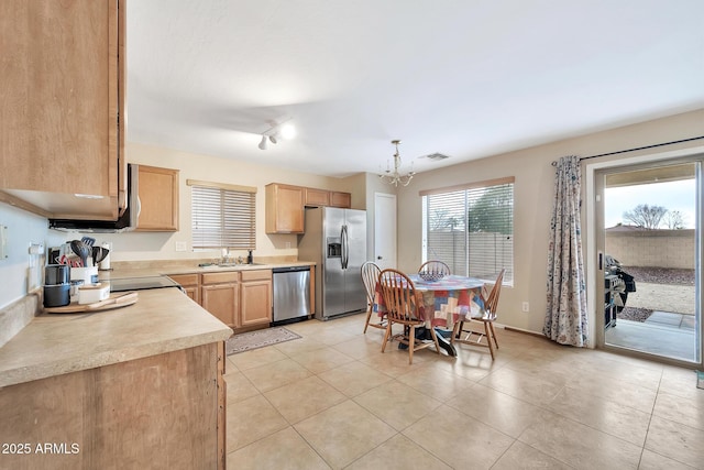 kitchen with appliances with stainless steel finishes, sink, a chandelier, hanging light fixtures, and light tile patterned floors