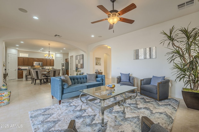 living room featuring ceiling fan with notable chandelier and light tile patterned floors