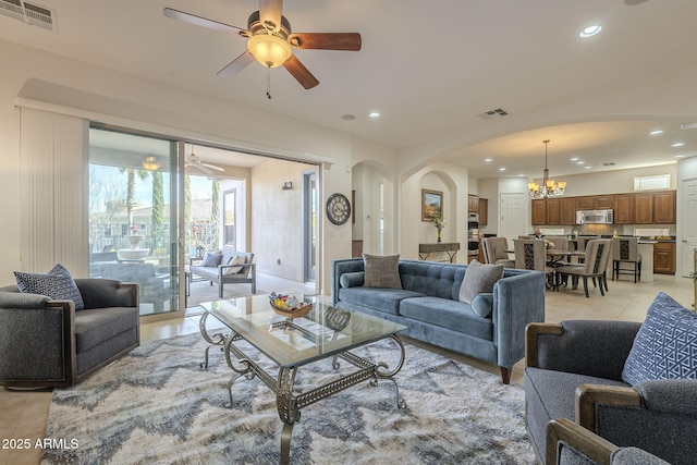 living room with light tile patterned floors and ceiling fan with notable chandelier