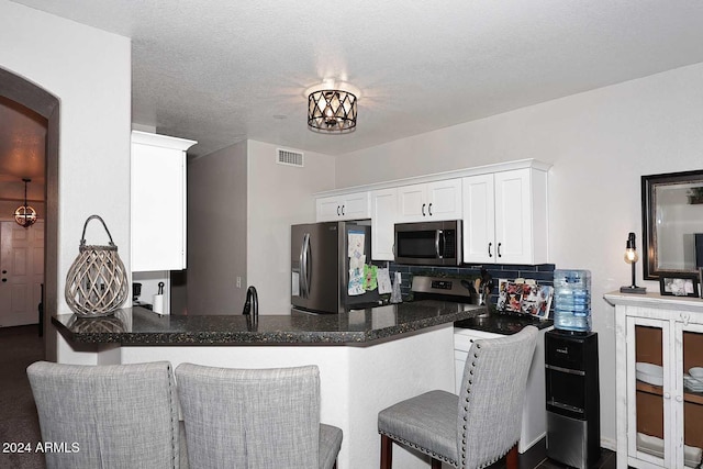 kitchen featuring white cabinets, sink, a textured ceiling, kitchen peninsula, and stainless steel appliances