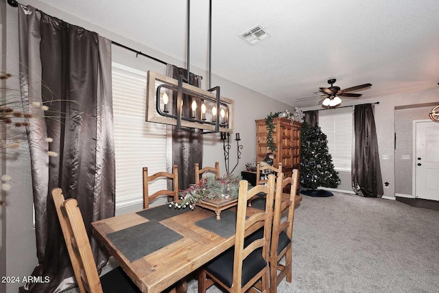 carpeted dining space with a textured ceiling and ceiling fan with notable chandelier