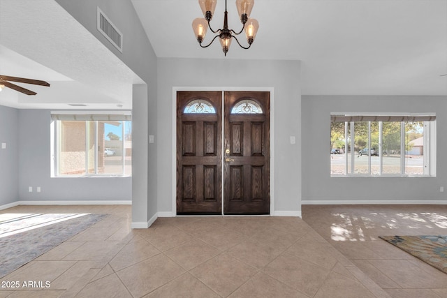 entryway with baseboards, ceiling fan with notable chandelier, visible vents, and light tile patterned flooring