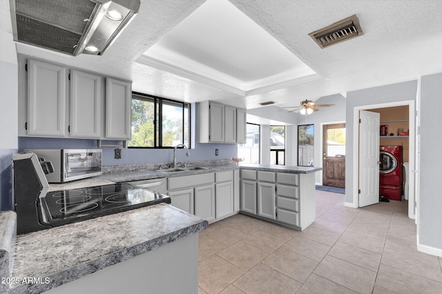 kitchen with light countertops, a tray ceiling, visible vents, and a sink