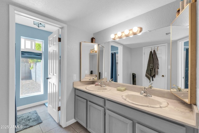 bathroom with double vanity, a sink, baseboards, and tile patterned floors