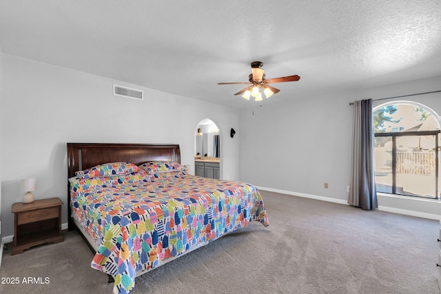 bedroom with arched walkways, a textured ceiling, visible vents, baseboards, and dark carpet