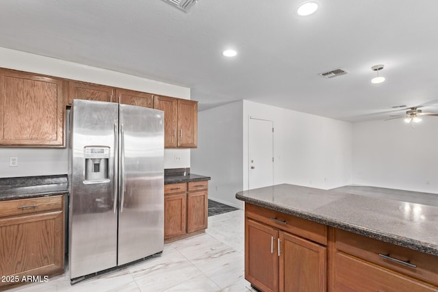kitchen with stainless steel fridge, ceiling fan, light marble finish flooring, brown cabinets, and recessed lighting