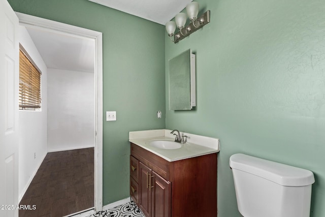 half bathroom with baseboards, vanity, and toilet