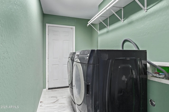 laundry room with a textured wall, washer and clothes dryer, and baseboards