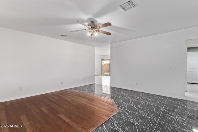 spare room with a ceiling fan and baseboards