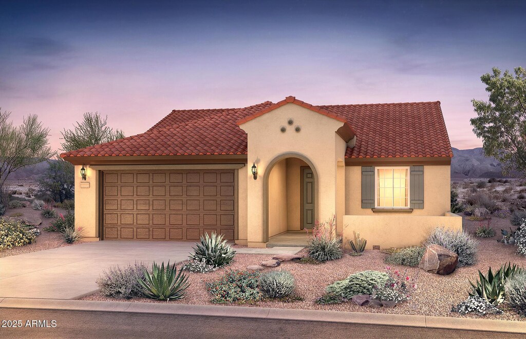 mediterranean / spanish home featuring an attached garage, stucco siding, concrete driveway, and a tile roof