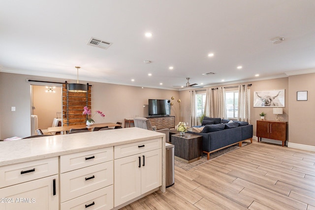 kitchen with visible vents, white cabinets, light wood-style flooring, light stone countertops, and pendant lighting