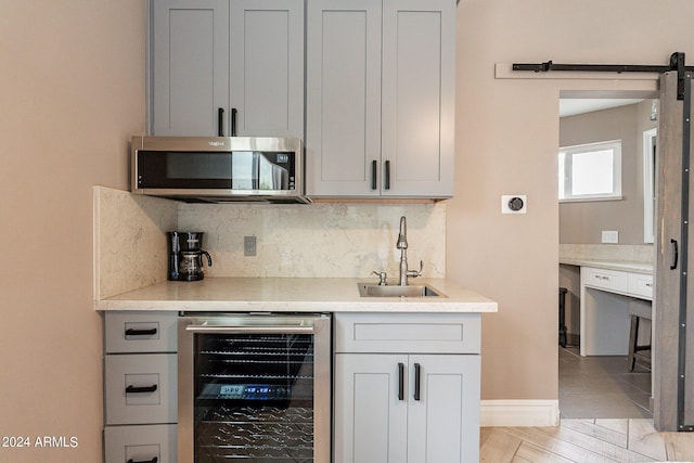 bar with beverage cooler, stainless steel microwave, decorative backsplash, and a sink