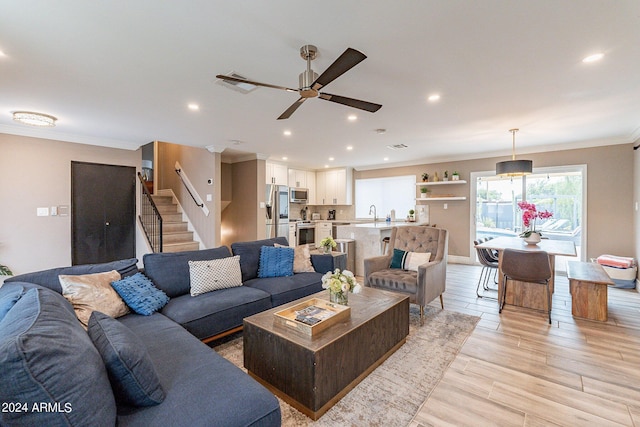 living room with light wood finished floors, recessed lighting, stairway, ornamental molding, and a ceiling fan