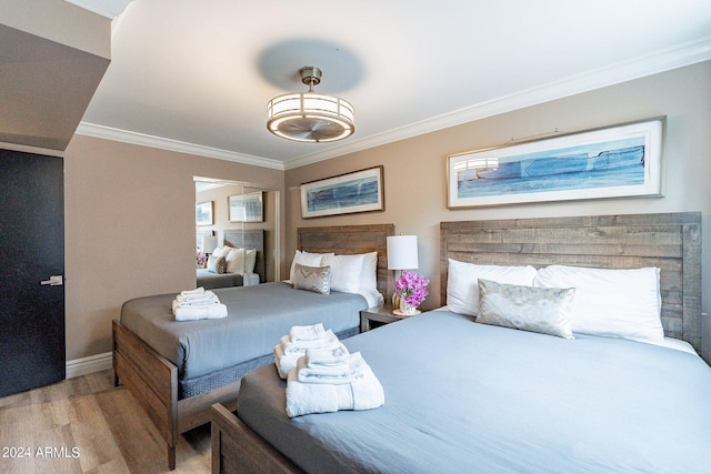 bedroom featuring light wood-style floors, baseboards, and ornamental molding