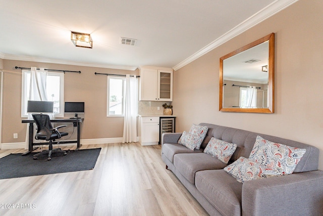 living room with ornamental molding, visible vents, light wood-style flooring, and baseboards