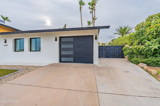 view of front facade featuring a garage, driveway, fence, and stucco siding