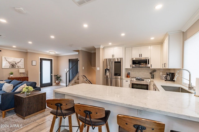 kitchen with appliances with stainless steel finishes, open floor plan, a sink, a peninsula, and a kitchen breakfast bar