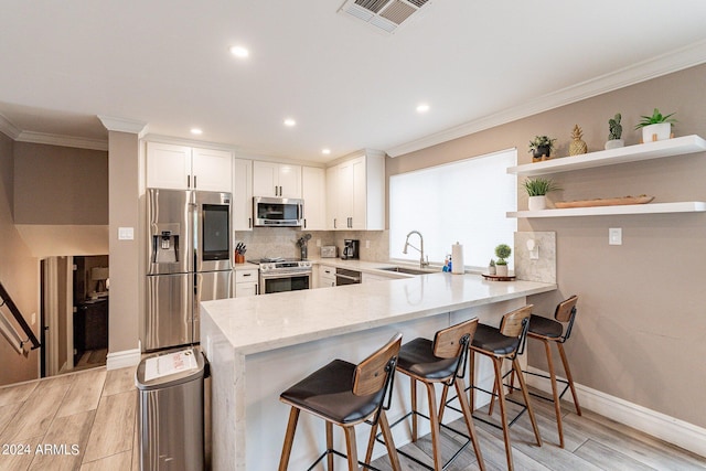 kitchen with visible vents, white cabinets, stainless steel appliances, a kitchen bar, and open shelves