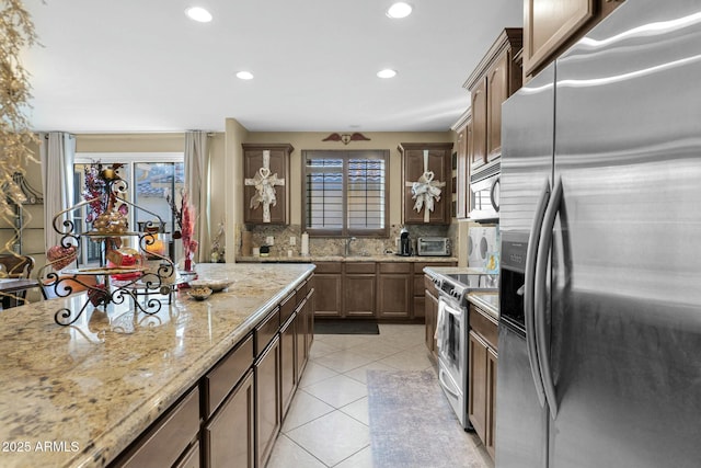 kitchen with backsplash, plenty of natural light, stainless steel appliances, and light stone countertops