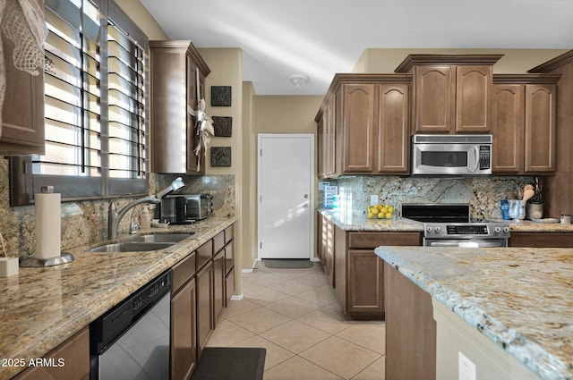 kitchen with tasteful backsplash, sink, light tile patterned floors, stainless steel appliances, and light stone countertops