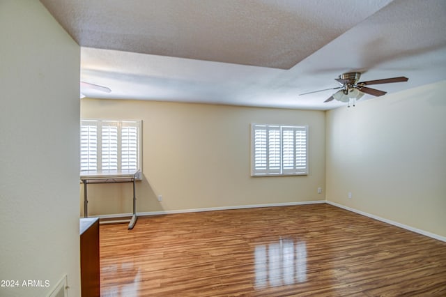 spare room with ceiling fan, a textured ceiling, wood-type flooring, and a healthy amount of sunlight