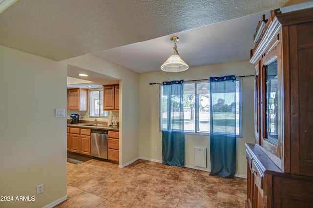 kitchen featuring decorative light fixtures, dishwasher, and sink