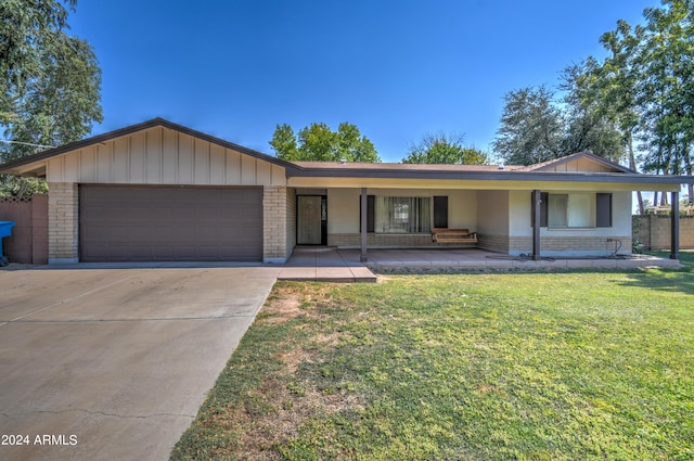 ranch-style home featuring a garage, a porch, and a front lawn