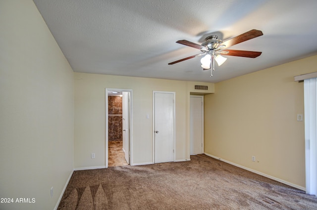 unfurnished bedroom with a textured ceiling, light colored carpet, and ceiling fan