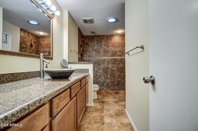 bathroom featuring tiled shower, vanity, and toilet