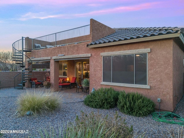 back of property featuring stucco siding, a patio, stairway, and a tiled roof