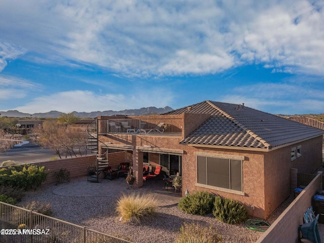 back of house featuring fence, a tile roof, stucco siding, a patio area, and a mountain view