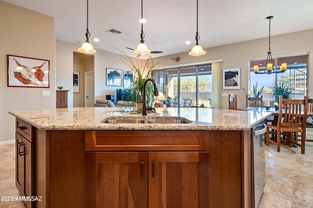 kitchen featuring visible vents, open floor plan, an island with sink, brown cabinets, and a sink